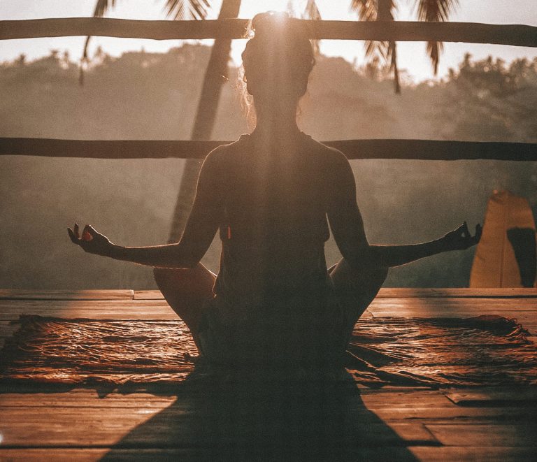 Meditating Person Silhouette of a person meditating indoors, sunlight streaming through trees.